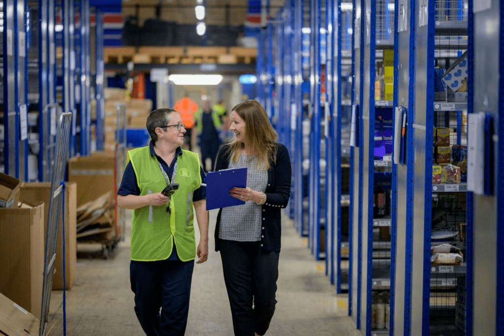 A warehouse manager walks through a fulfillment center with a coworker – AMS Fulfillment