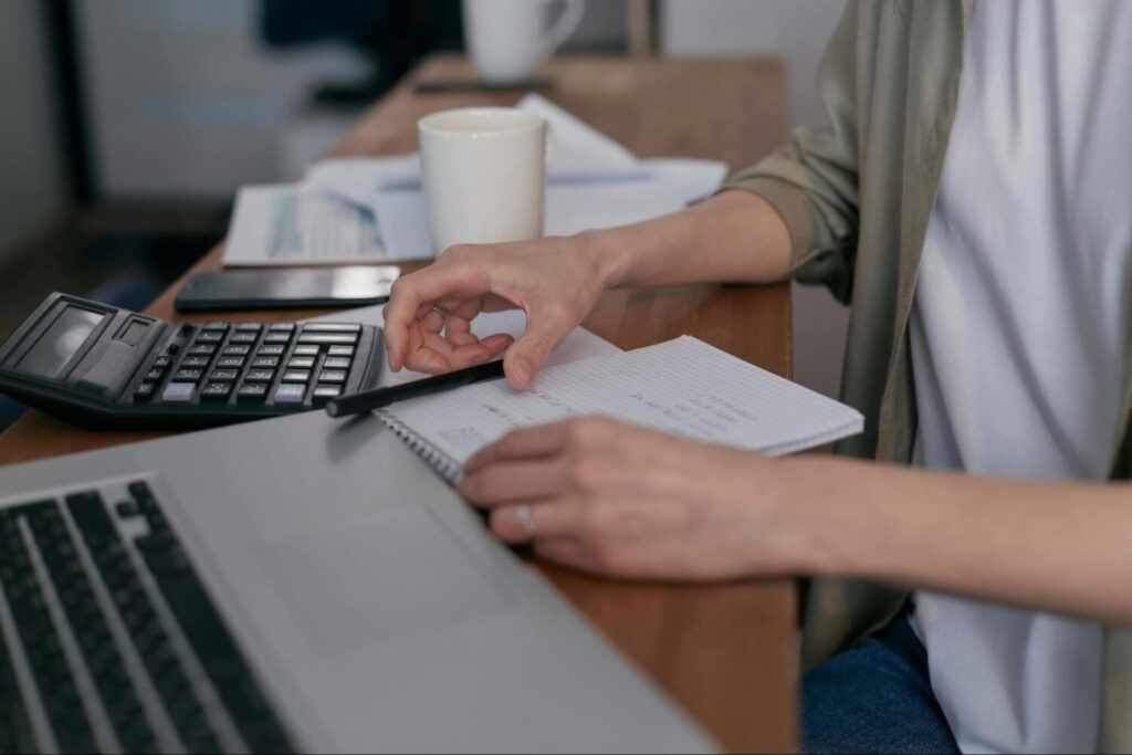 A person uses calculator and takes note on a notepad – AMS Fulfillment